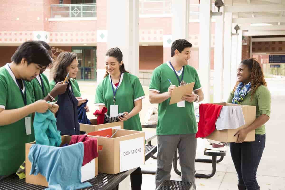 Group of college student volunteers collect clothing donations. Charity.